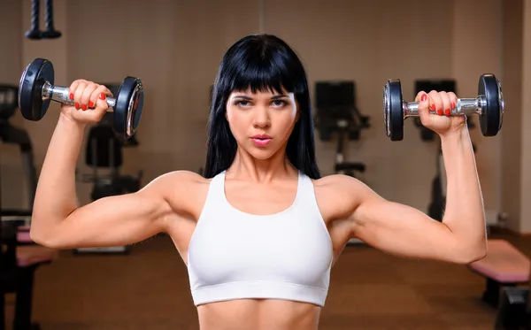 Schöne junge Frau trainiert im Fitnessclub — Stockfoto