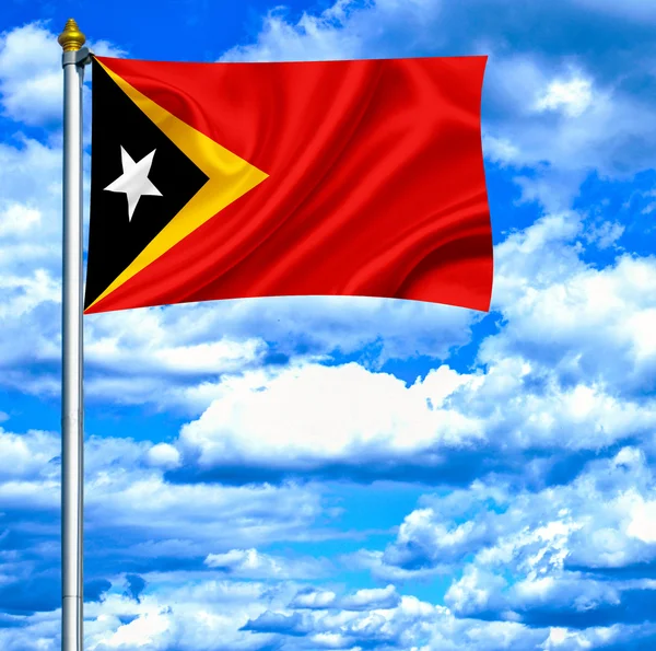 Východní timor mává vlajkou proti modré obloze — Stock fotografie