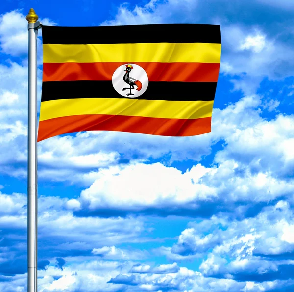 Uganda mává vlajkou proti modré obloze — Stock fotografie