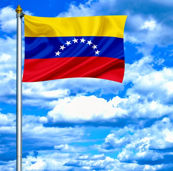 Venezuela mává vlajkou proti modré obloze — Stock fotografie