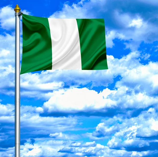 Nigérie mává vlajkou proti modré obloze — Stock fotografie