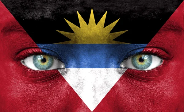 Menschengesicht bemalt mit Flagge von Antigua und Barbuda — Stockfoto