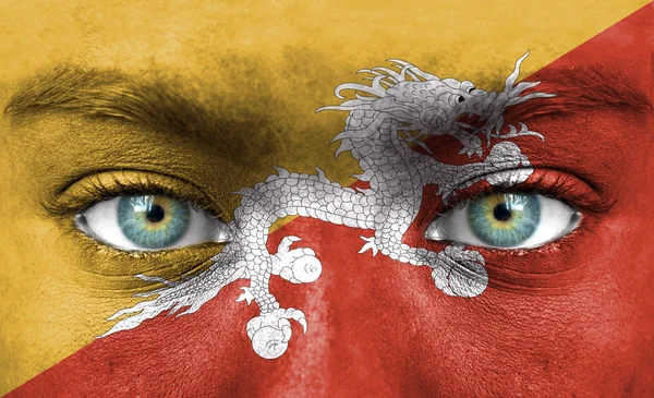 Lidská tvář s Bhútánská vlajka — Stock fotografie