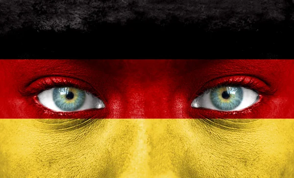 Человеческое лицо, раскрашенное флагом Германии — стоковое фото