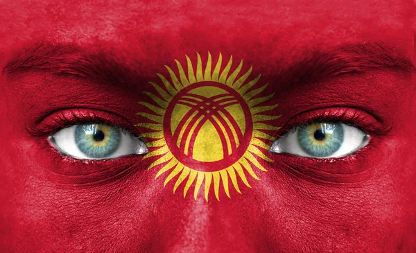 Menschengesicht mit Fahne von Kyrgyzstan bemalt — Stockfoto
