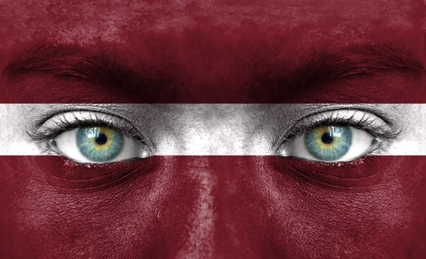 Menselijk gezicht beschilderd met vlag van Letland — Stockfoto