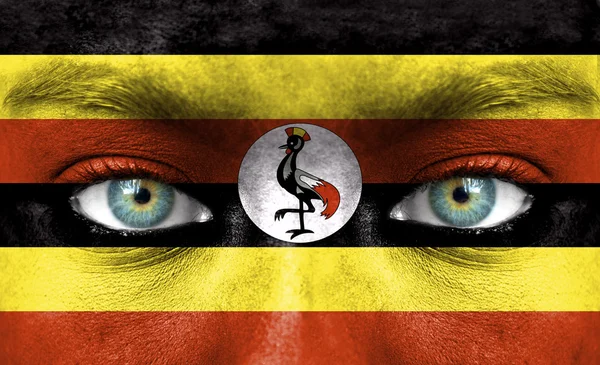 Menselijk gezicht beschilderd met vlag van Oeganda — Stockfoto