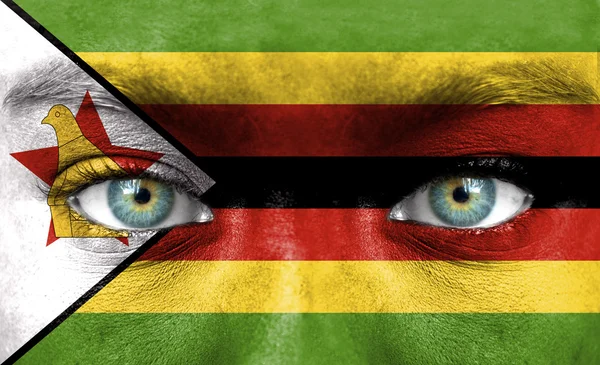 Rosto humano pintado com bandeira do Zimbabué — Fotografia de Stock