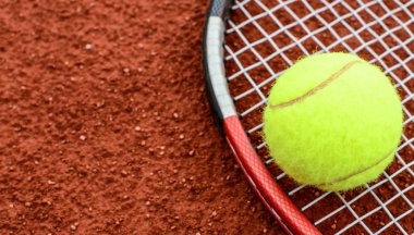Tennis ball and racquet on clay macro shot