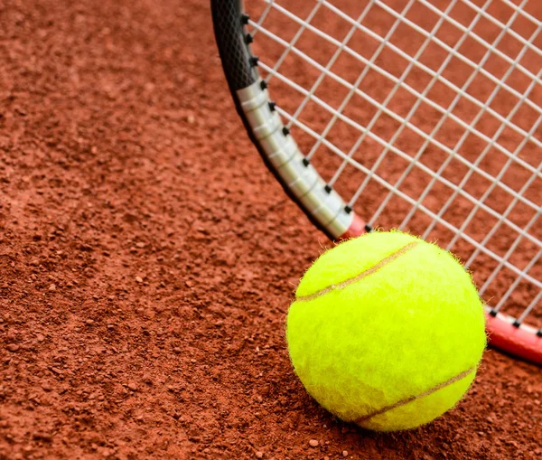 Теннисный мяч и ракетка на теннисной глиняной корте — стоковое фото