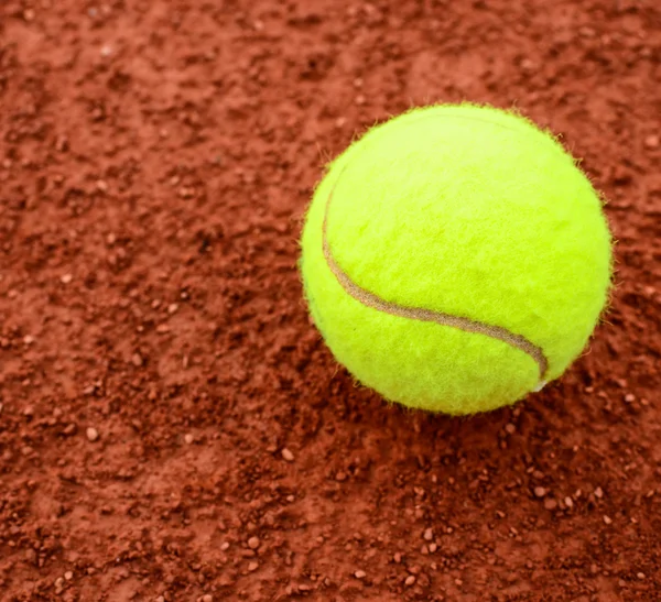 Bola de tênis em um campo de barro de tênis — Fotografia de Stock