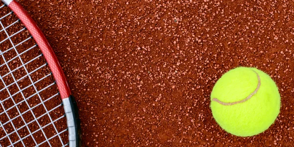 Теннисный мяч и ракетка на глиняной площадке — стоковое фото