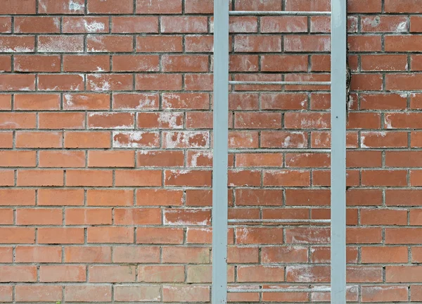 Oude metalen ladder op een bakstenen muur — Stockfoto