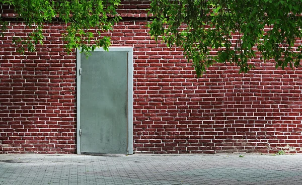 Серая металлическая дверная текстура с железной ручкой и кирпичной стеной — стоковое фото