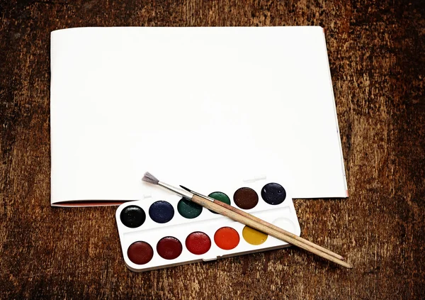 Konstnärliga och borstar för att färg och papper på träbord — Stockfoto