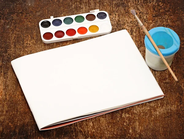 Set of art paints and brushes to paint and paper on wooden table — Stock Photo, Image