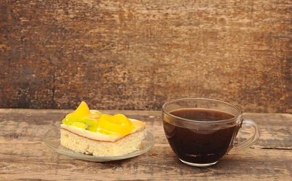 Μεγέθυνση του γυαλιού φλυτζάνι καφέ και βερίκοκο κέικ σε ξύλινο τραπέζι — Φωτογραφία Αρχείου
