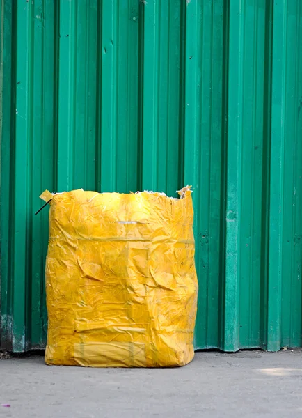 Gul sopor påse främre gröna staket — Stockfoto