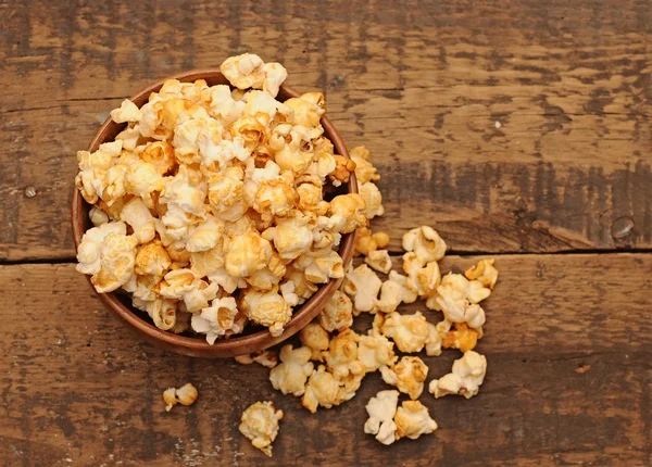 Popcorn v dřevěné misce na dřevěný stůl — Stock fotografie