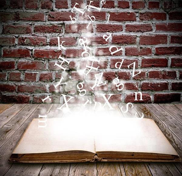 An open book with letters falling into the pages — Stock Photo, Image