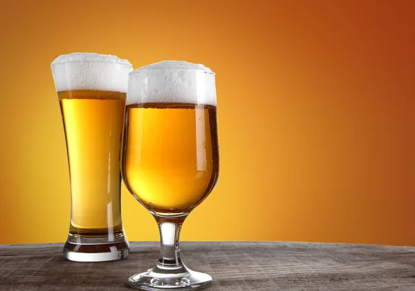 ゴールドの背景を持つガラスのビール — ストック写真