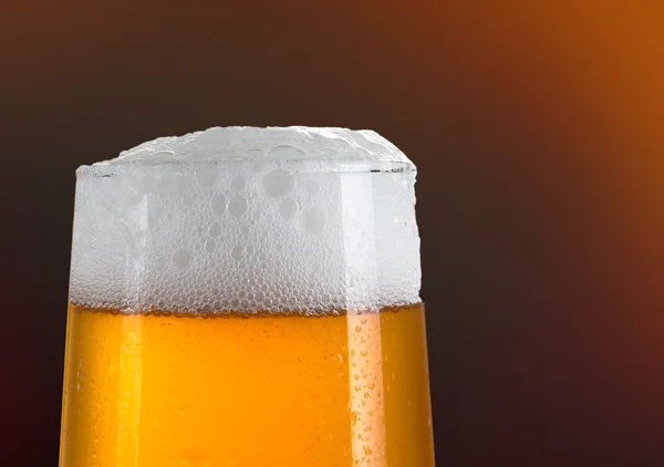 Birra in un bicchiere con fondo oro — Foto Stock