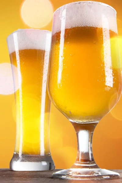 Bière dans un verre avec fond doré — Photo