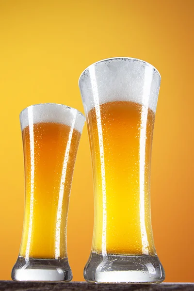 Bière dans un verre avec fond doré — Photo