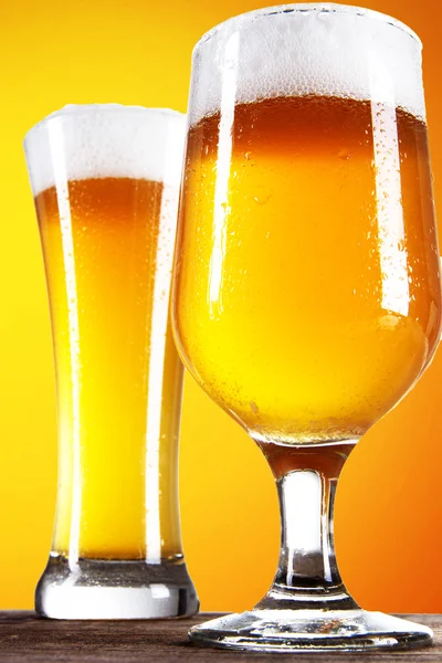 ゴールドの背景を持つガラスのビール — ストック写真