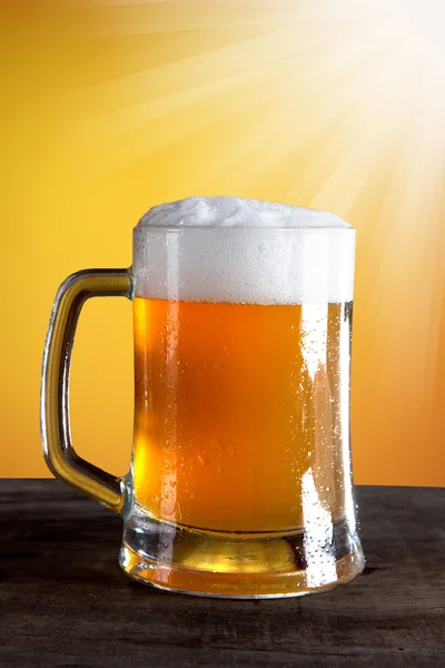 Cerveja em um copo com fundo dourado — Fotografia de Stock