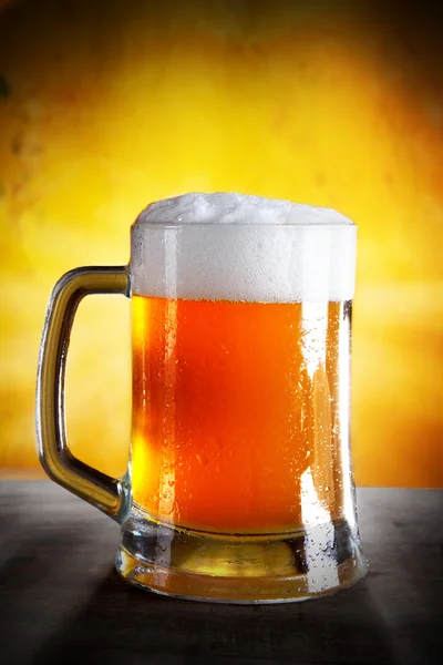 Bier im Glas mit goldenem Hintergrund — Stockfoto
