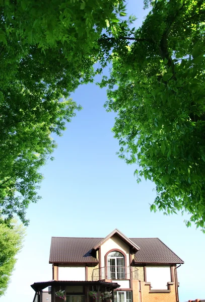 Vackert hus under bågen av träd — Stockfoto