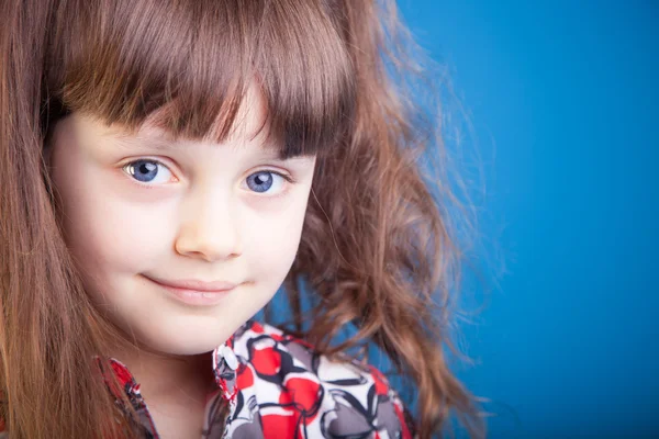 Vacker liten flicka på en blå bakgrund — Stockfoto