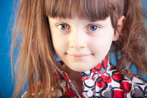 Schönes kleines Mädchen auf blauem Hintergrund — Stockfoto