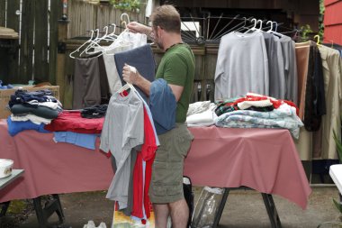 Man Holding Clothes at Sale clipart