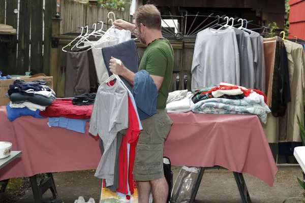 Homem segurando roupas à venda — Fotografia de Stock