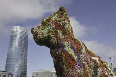 bilbao şehrinde bir gökdelenin önünde çiçek heykel