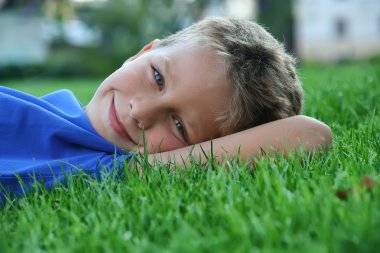 Boy laying on a green grass clipart