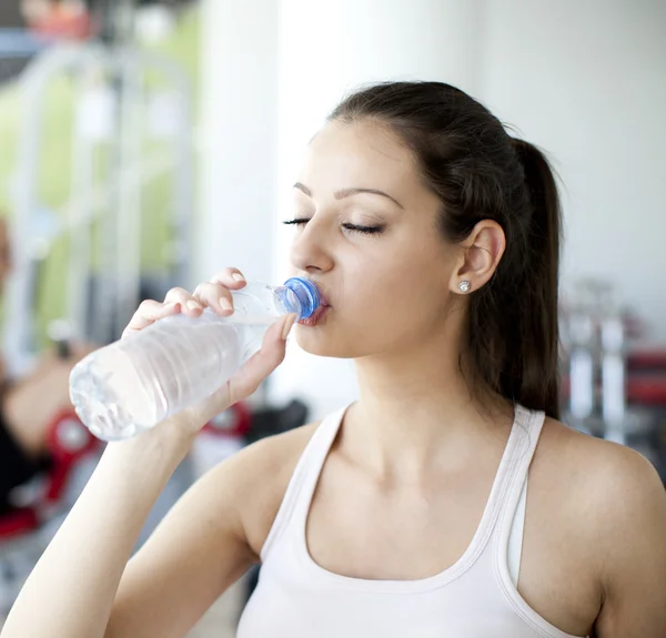 Chica bebiendo agua en el gimnasio — Foto de Stock