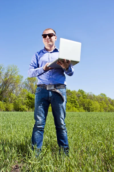 Businessmanon meadow, with a laptop Stock Photo