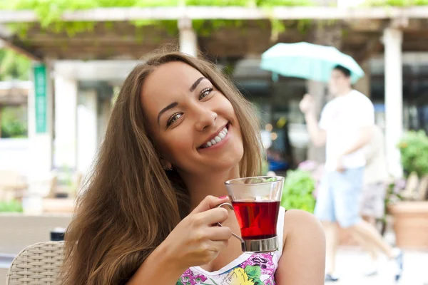 Mujer joven bebiendo té en un café al aire libre —  Fotos de Stock