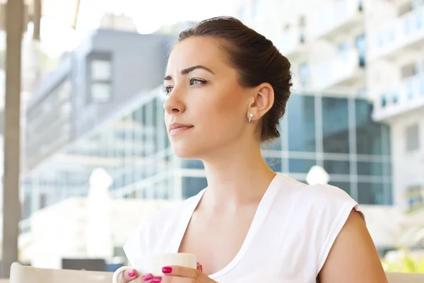 Młoda kobieta pije herbatę w kawiarni na świeżym powietrzu — Zdjęcie stockowe