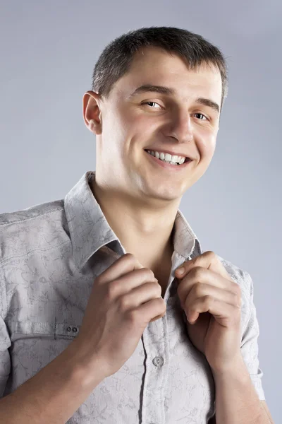Портрет счастливого улыбающегося молодого человека в серой рубашке — стоковое фото