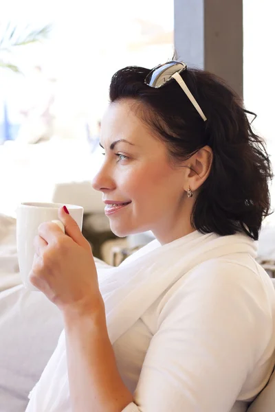 Bir kahve ile bir kafede oturan genç çekici kadın — Stok fotoğraf