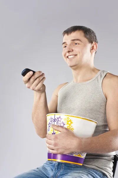 Молодий чоловік дивиться телевізор з попкорном — стокове фото