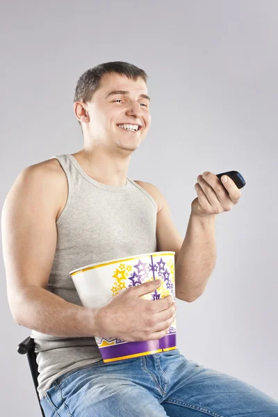 Молодой человек смотрит телевизор с попкорном — стоковое фото