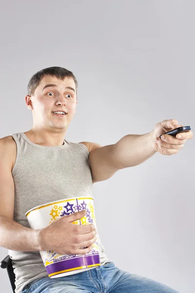 Young man watching television with popcorn — Stock Photo, Image