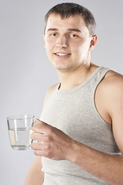 Junger schöner Mann trinkt Mineralwasser — Stockfoto