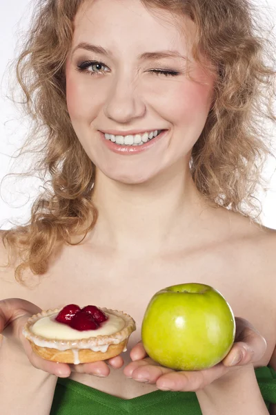 Hermosa rubia eligiendo, entre una manzana y un pastel — Foto de Stock