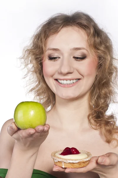 Красивая блондинка выбирает между яблоком и тортом — стоковое фото